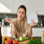 portrait woman checking grocery list looking vegetables holding notebook reading recipe while 1290x750 1