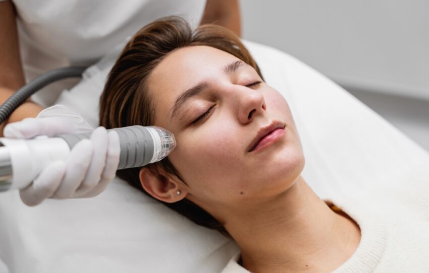 What to Expect During Your First Quantum RF Session 5 Gloved provider guiding a radiofrequency handpiece along a patient's cheek during a first Quantum RF session at an aesthetic clinic