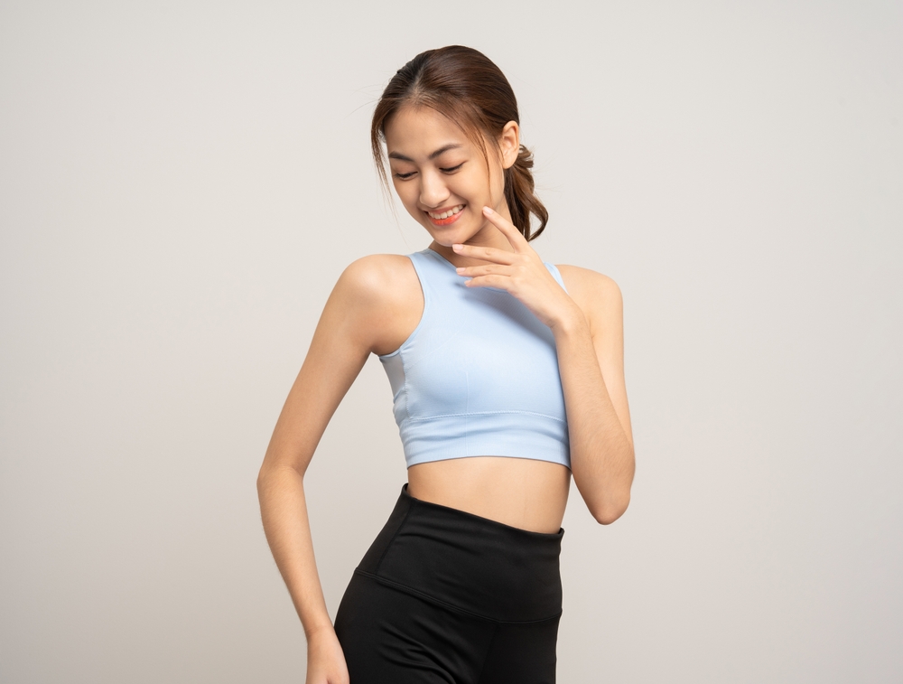 Smiling woman in activewear with a toned midsection representing a confident Quantum RF candidate who has achieved body contouring results