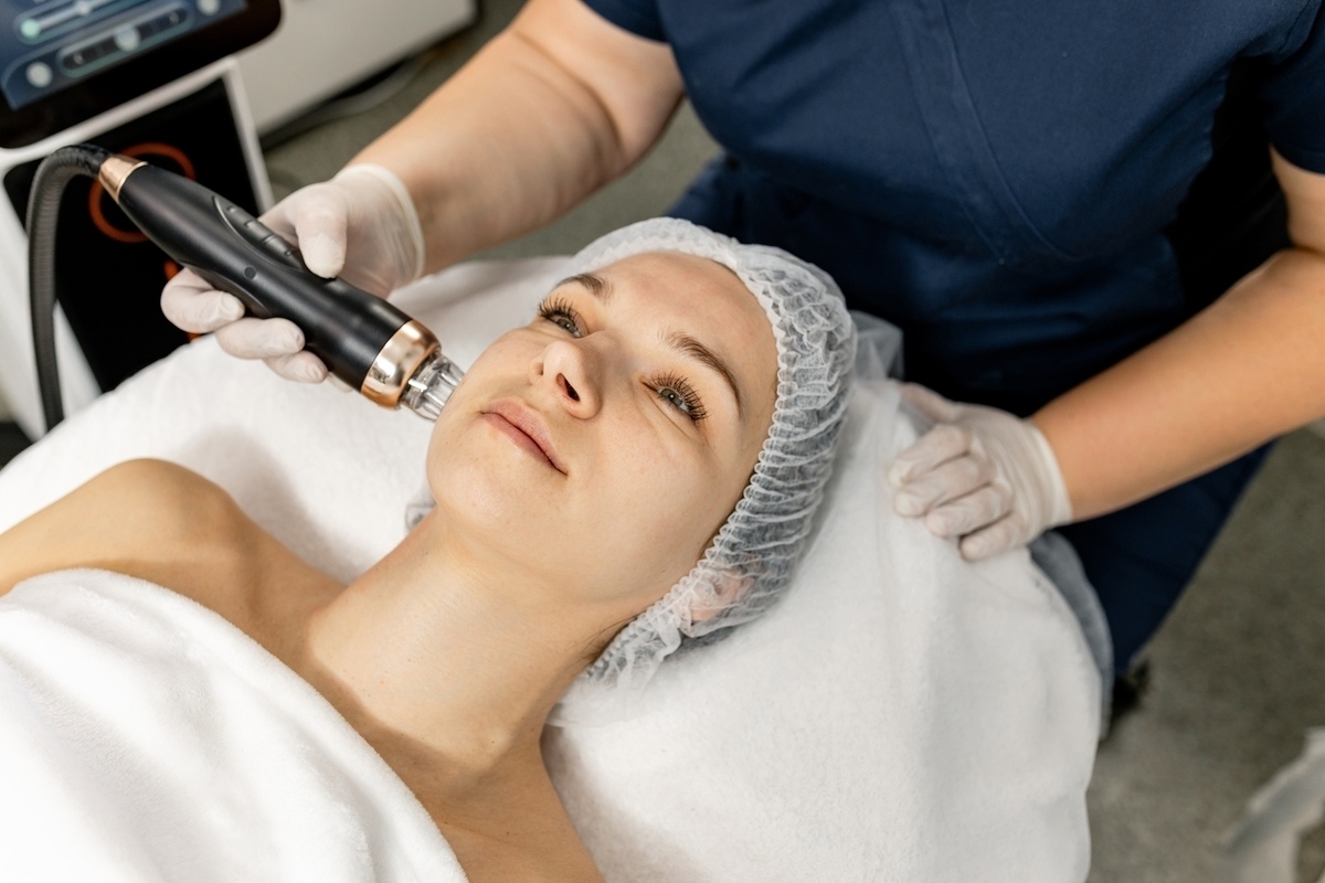 Provider applying a Quantum RF vs Morpheus8 radiofrequency handpiece to a patient's cheek during a non-surgical facial skin tightening treatment session